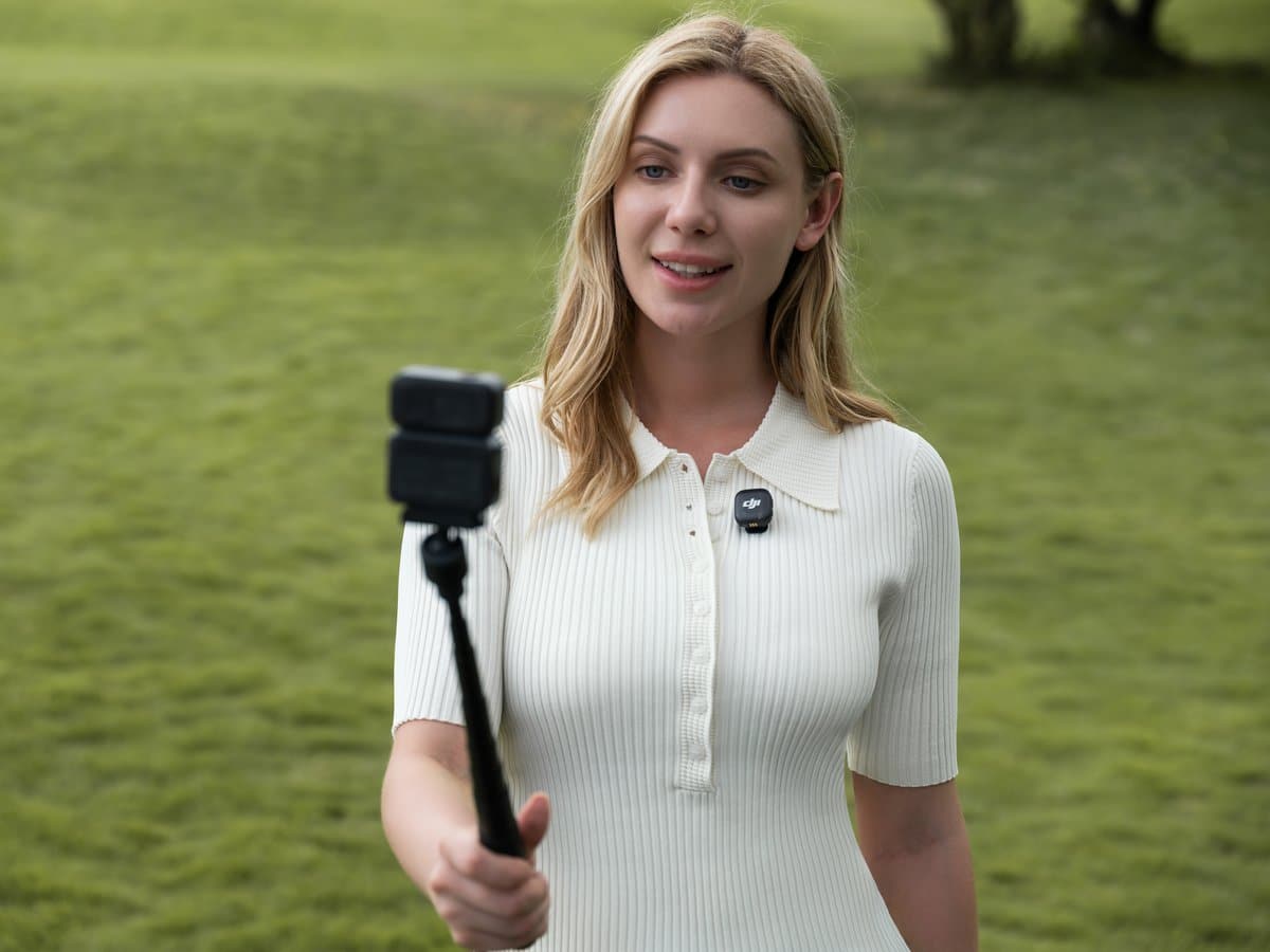 Cô gái cầm DJI Osmo Nano gắn gậy selfie quay vlog du lịch ngoài trời